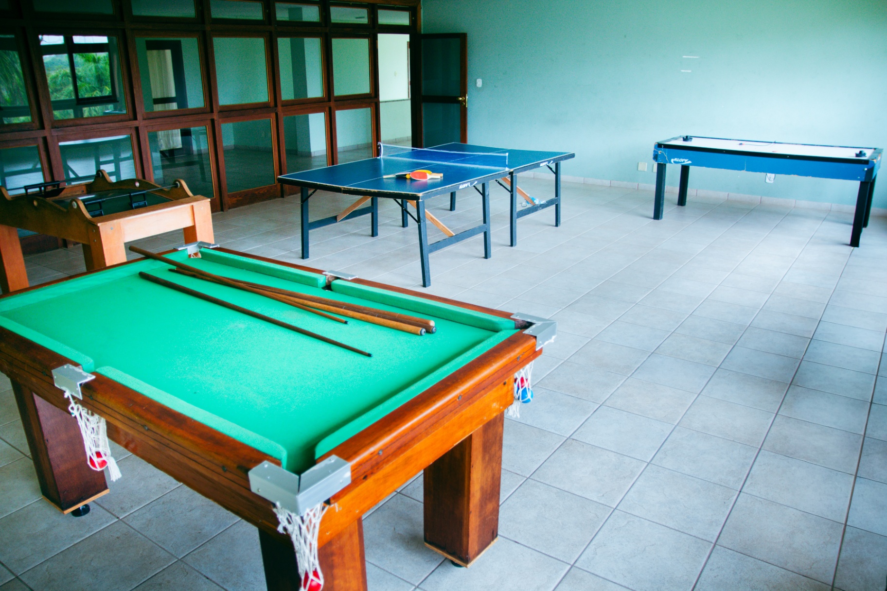 Sala de jogos com sinuca, pingue-pongue, pebolim e aero hockey